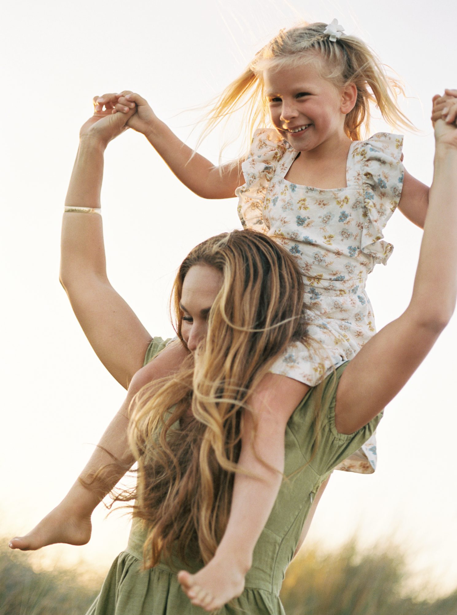 Daughter on mom's shoulders at the beach